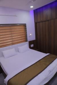 a bedroom with a large white bed and a wooden door at Gulmohar Homes in Udaipur