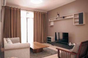 ein Wohnzimmer mit einem Sofa, einem Tisch und einem TV in der Unterkunft Charming Waterside Escape in Entebbe
