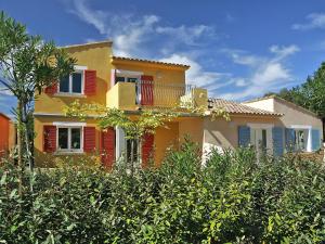 博爾戈的住宿－Lovely apartment in Borgo with shared pool，黄色的房屋,有红色的百叶窗和树木