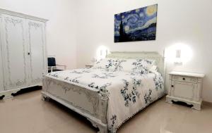 a bedroom with a white bed and a painting on the wall at Balcone in Valle d'Itria in Martina Franca
