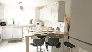 eine Küche mit weißen Schränken und einem Tisch mit Stühlen in der Unterkunft Relaxing 3 Bedroom Norwich Haven in Norwich