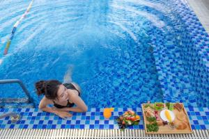 a woman in a swimming pool with a plate of food at Xavia Hotel in Nha Trang