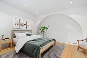 a white bedroom with a bed and an arched window at Cozy 3 Bedroom House Annandale in Sydney