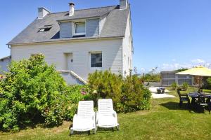 two white chairs and a table in front of a house at Holiday home in Perros Guirec in Perros-Guirec