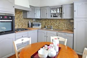 a kitchen with white cabinets and a wooden table at Holiday home in Perros Guirec in Perros-Guirec