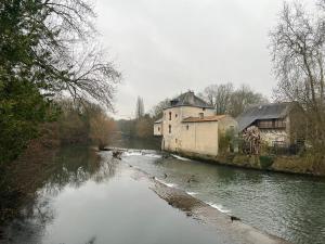 einen Fluss mit Häusern und Gebäuden neben einem Fluss mit Bäumen in der Unterkunft Le Moulin du Clain - Jolie maison à Poitiers in Poitiers