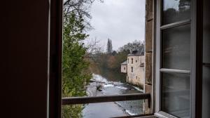 une fenêtre avec vue sur la rivière et les bâtiments dans l'établissement Le Moulin du Clain - Jolie maison à Poitiers, à Poitiers