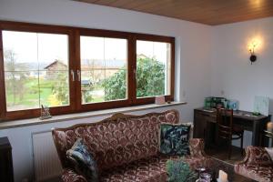 a living room with a couch and a desk and windows at ZumGlückFrei in Passau