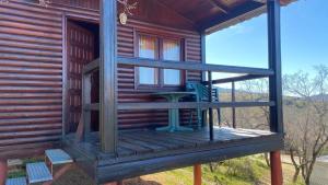 a porch of a log cabin with a blue chair on it at Camping de Cervera de Buitrago in Cervera de Buitrago