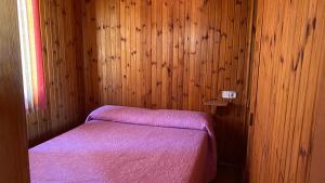 a bedroom with a purple bed in a wooden wall at Camping de Cervera de Buitrago in Cervera de Buitrago