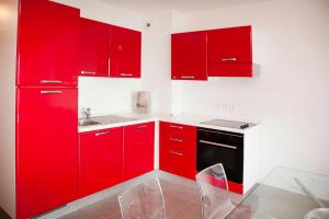uma cozinha vermelha com armários vermelhos e um lavatório em Res Villa Tyrrenia Macinaggio Rogliano Apartment with bay view em Macinaggio