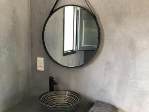 een badkamer met een ronde spiegel en een wastafel bij Les Jardins d Eve Solenzara townhouse with private pool in Favone