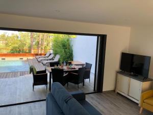 a living room with a table and chairs and a television at Les Jardins d Eve Solenzara townhouse with private pool in Favone