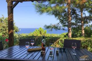 a wooden table with wine glasses and a bottle of wine at Res Mare e Monte Solenzara Bungalow with terrace in Favone
