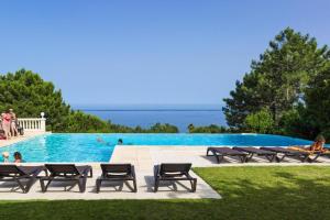 a swimming pool with chairs and the ocean in the background at Res Mare e Monte Solenzara Bungalow with terrace in Favone