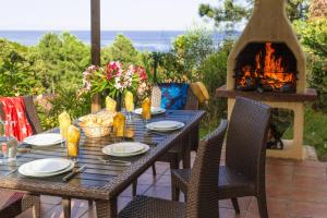 - une table avec des chaises et une cheminée sur la terrasse dans l'établissement Res Mare e Monte Solenzara Bungalow with terrace, à Favone