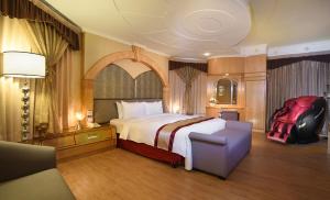 1 dormitorio grande con 1 cama grande y 1 silla en Natoli Motel, en Tainan