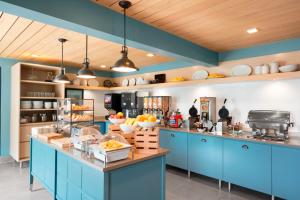 Country Inn & Suites by Radisson, Minneapolis West, MN في بليموث: مطبخ مع خزائن زرقاء وكاونتر مع الطعام