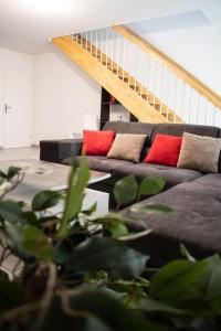 ein Wohnzimmer mit einem Sofa mit zwei roten Kissen in der Unterkunft Duplex avec jardin - 2 parkings privés - 2 chambres in Cornebarrieu