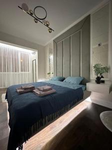 ein Schlafzimmer mit einem großen Bett mit blauer Bettwäsche in der Unterkunft Business class apartments in Almaty in Almaty