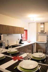 eine Küche mit einem Tisch mit Tellern und Weingläsern in der Unterkunft Duplex avec jardin - 2 parkings privés - 2 chambres in Cornebarrieu