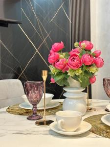 einen Tisch mit einer Vase voller rosa Rosen in der Unterkunft Business class apartments in Almaty in Almaty