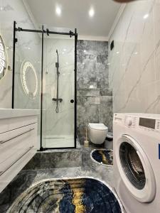 ein Bad mit einer Dusche und einer Waschmaschine in der Unterkunft Business class apartments in Almaty in Almaty