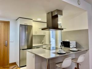 a kitchen with a stainless steel refrigerator and white cabinets at Cíes Premium Suitel García Barbón 73 - Love your Stay in Vigo