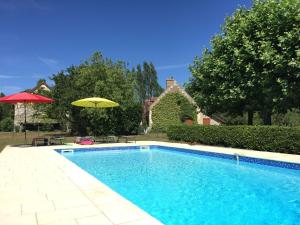 a swimming pool with an umbrella next to a house at Charming Holiday Home in Montrichard with Pool in Bourré