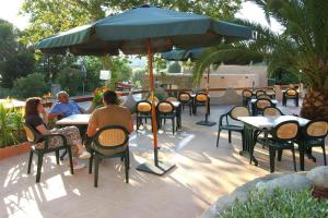 a group of people sitting at tables under an umbrella at Residence Les Dauphins in Tiuccia with balcony in Casaglione