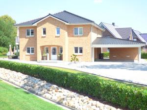 a brick house with a hedge in front of it at Villa Kanalblick, Schiffsdeck in Oldenbüttel