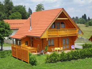 een houten huis met een oranje dak bij Holiday home our little hunting lodge in Philippsreut