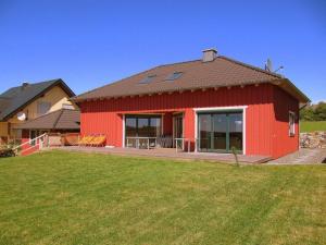 una casa roja con un césped verde delante de ella en Holiday home Red Milan, en Irmenach