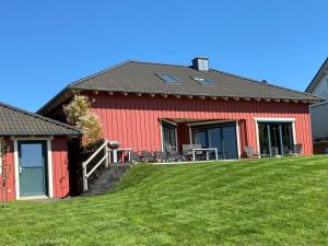 une maison rouge avec une pelouse devant elle dans l'établissement Holiday home Red Milan, à Irmenach