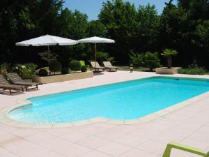 uma piscina com cadeiras e guarda-sóis em Lovely Cottage in Valr as with Swimming Pool em Valréas