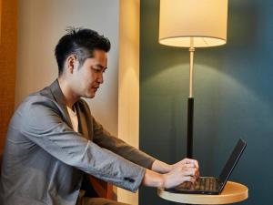 a man working on a laptop computer next to a lamp at Kansai Airport Washington Hotel in Izumi-Sano