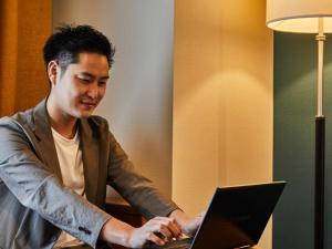 a man sitting at a table using a laptop computer at Kansai Airport Washington Hotel in Izumi-Sano
