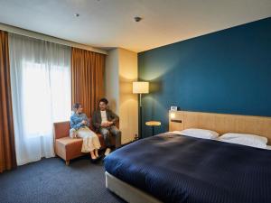 Due donne sedute in una camera d'albergo con un letto di Kansai Airport Washington Hotel a Izumisano