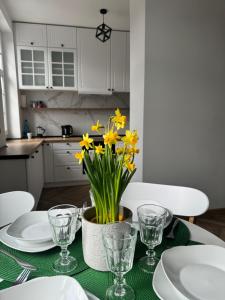a dining room table with yellow daffodils on it at Ogarna 33 studios in Gdańsk
