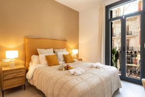 een slaapkamer met een bed met witte lakens en een raam bij Lodging Apartments Rambla Poblenou 12 in Barcelona