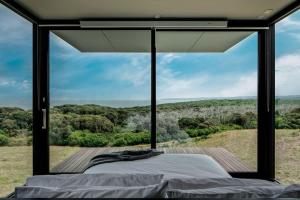 a bed in a room with a large window at Sky Pod 1 - Luxury Off-Grid Eco Accommodation in Cape Otway