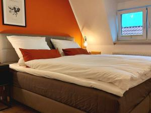uma cama grande num quarto com uma parede laranja em Dornbusch Apartment 3 em Steinhude