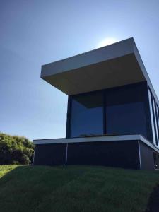 ein Gebäude mit einem großen Fenster auf einem Grasfeld in der Unterkunft Sky Pod 2 - Luxury Off-Grid Eco Accomodation in Cape Otway