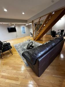 un sofá de cuero negro en una sala de estar con una escalera en Executive Suite in a Victorian Style Bungalow P4b en Pickering