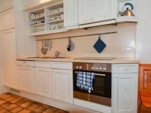 een keuken met witte kasten en een fornuis bij Holiday home Waldhaus am Burbach in Bad Berleburg