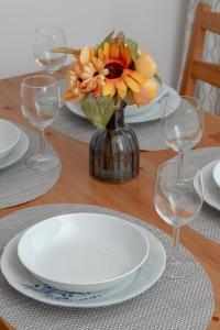 a table with plates and a vase with flowers on it at Apartments Łagiewniki Gdańsk by Renters in Gdańsk
