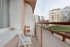 a balcony with two white chairs and a window at Apartments Łagiewniki Gdańsk by Renters in Gdańsk