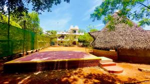 un edificio con techo de paja junto a una valla en Lotus Garden - Near Matrimandir Center Auroville, en Auroville