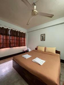een slaapkamer met een bed en een plafondventilator bij Thakhek Travel Lodge in Thakhek