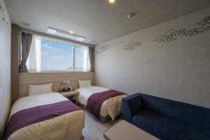 出雲市にある湖畔の温泉 くにびきのベッド2台、ソファ、窓が備わる客室です。